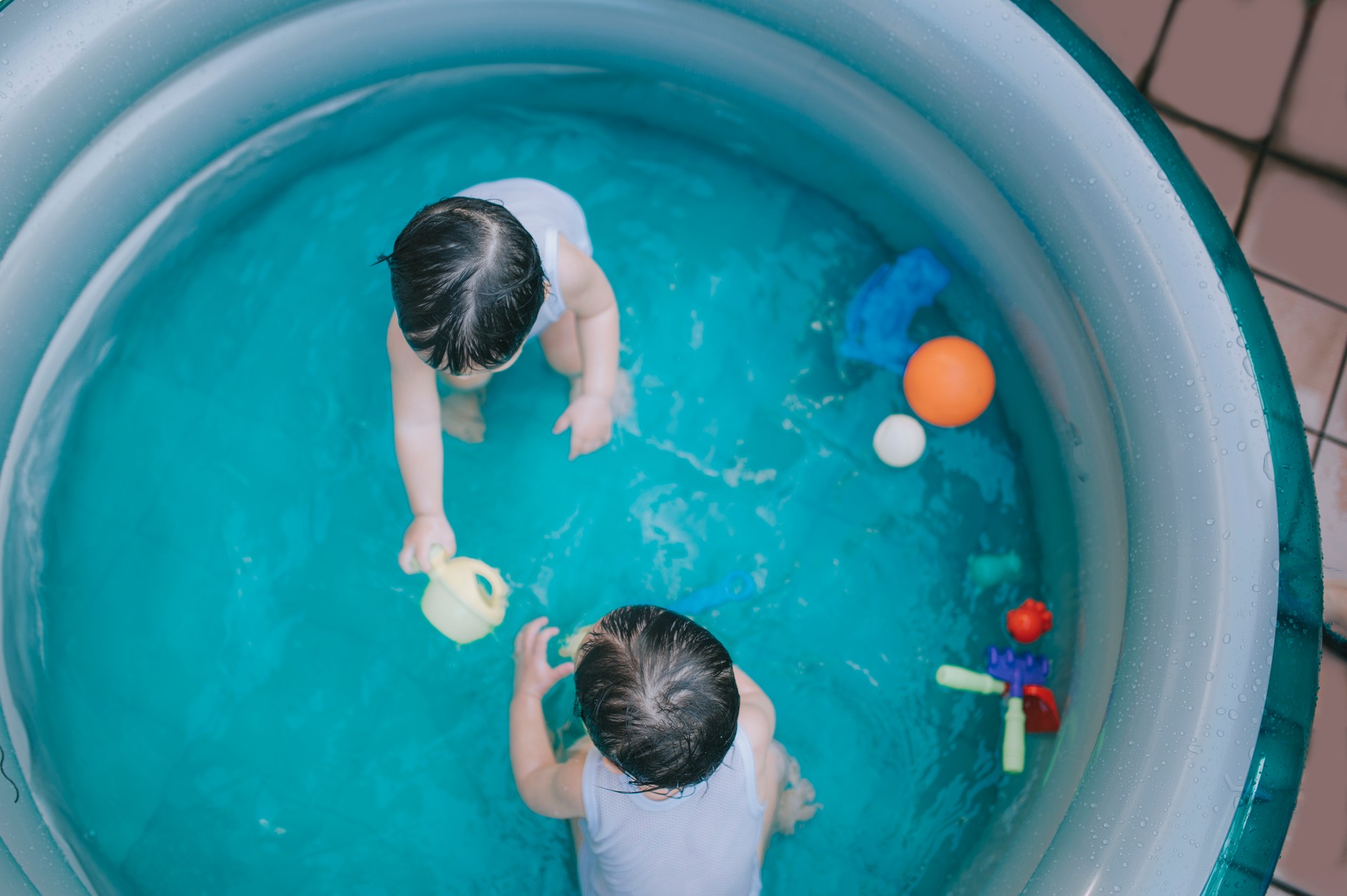 directly above asian chinese twin babies boys playing in inflatable swimming pool during summer at backyard of house